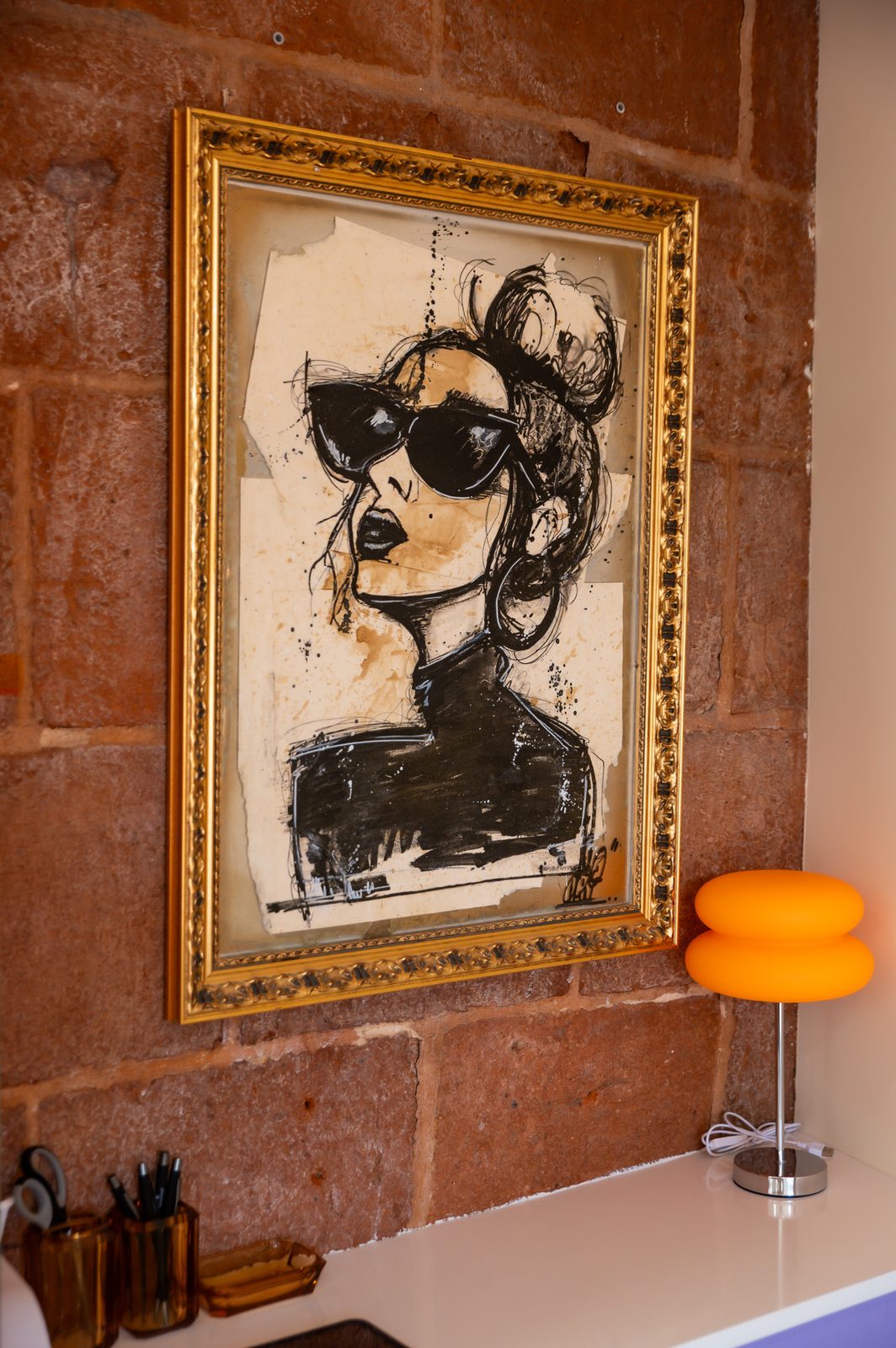 Décor seventies : œuvre encadrée, mur de briques et tabourets orange chez Anna Marini